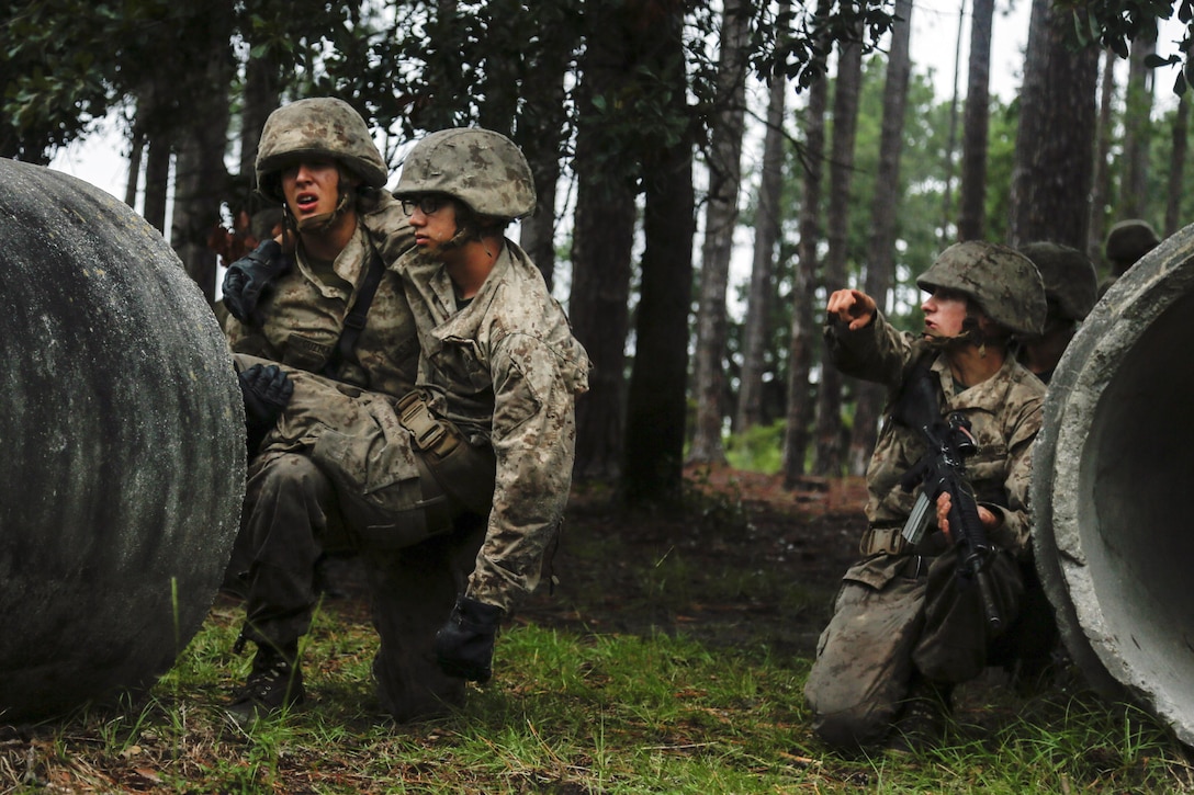 Three Marines make their way through a forested area