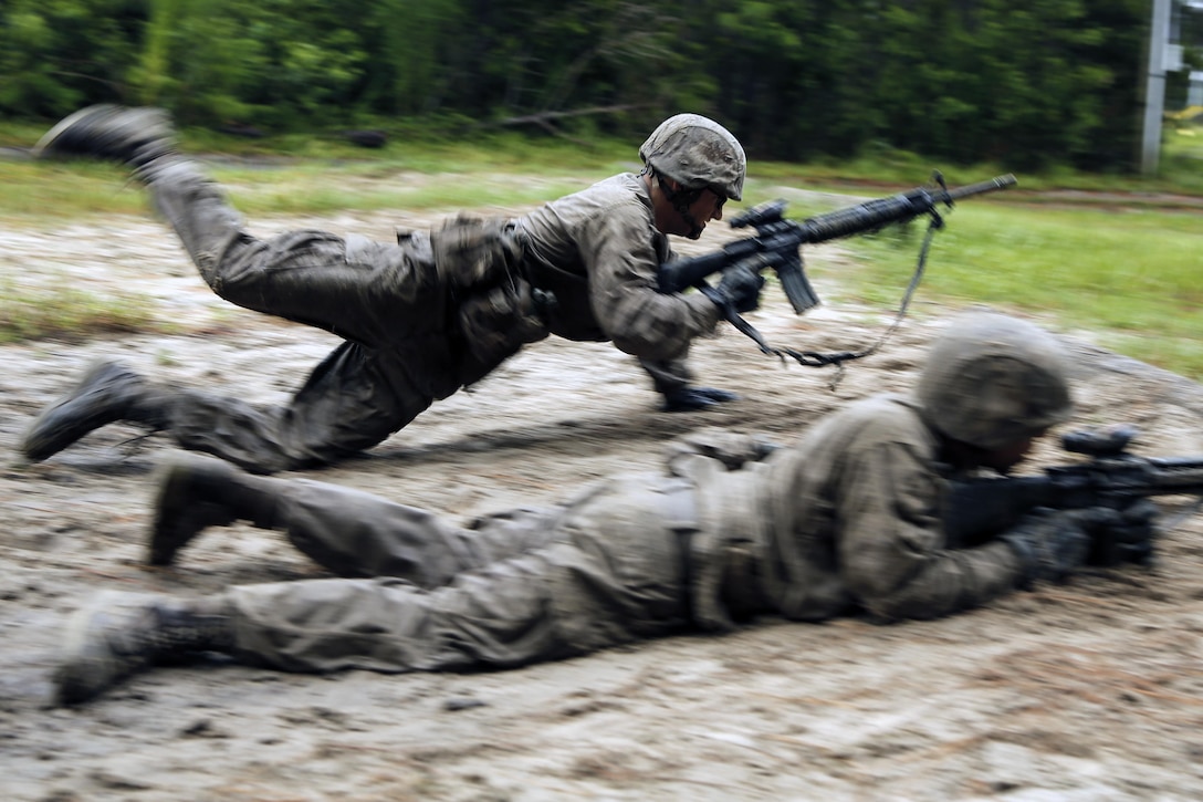 A Marine dives into the mid next to other Marines.