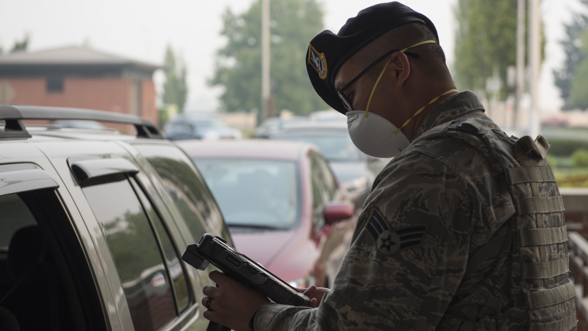 Senior Airman Alfonso Deleon Guerrero, 92nd Security Forces Squadron installation entry controller, checks identification for base entry during hazardous air quality conditions Sept. 7, 2017, at Fairchild Air Force Base, Washington. Masks and respirators can help filter out harmful particles and gases, although state health officials advise remaining indoors until air quality improves. (U.S. Air Force Photo by: Airman 1st Class Ryan Lackey)