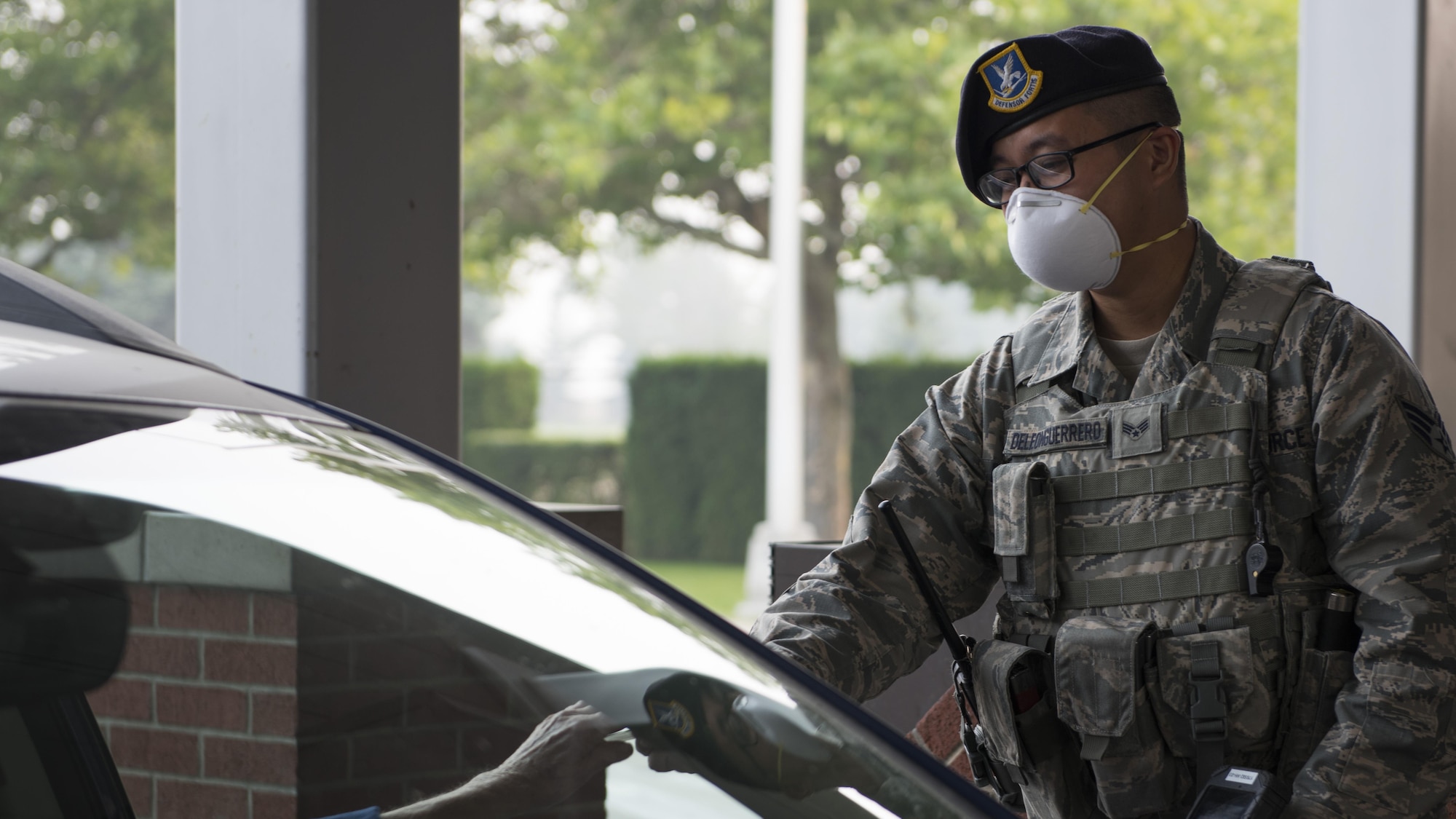 Senior Airman Alfonso Deleon Guerrero, 92nd Security Forces Squadron installation entry controller, checks identification for base entry during hazardous air quality conditions Sept. 7, 2017, at Fairchild Air Force Base, Washington. Health advisories and outside work restrictions have been instituted on base to reduce the environmental risk to Airmen. (U.S. Air Force Photo by: Airman 1st Class Ryan Lackey)