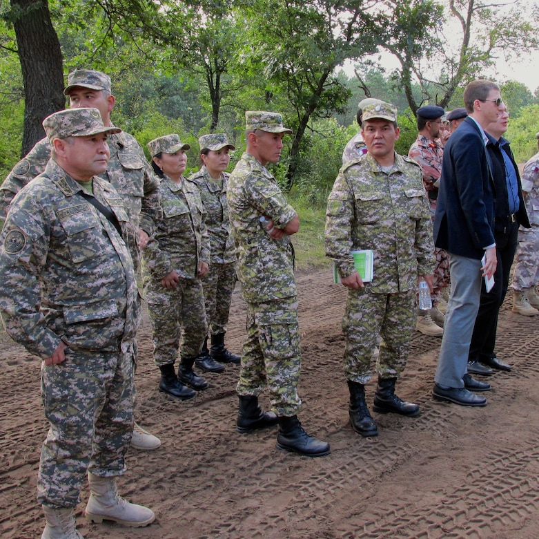 U.S. Army soldiers in uniform and civilians standing in a group in front of trees