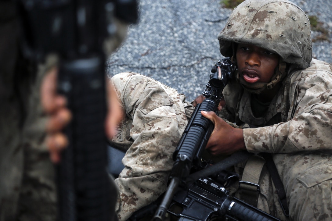 A Marine kneels on the ground.