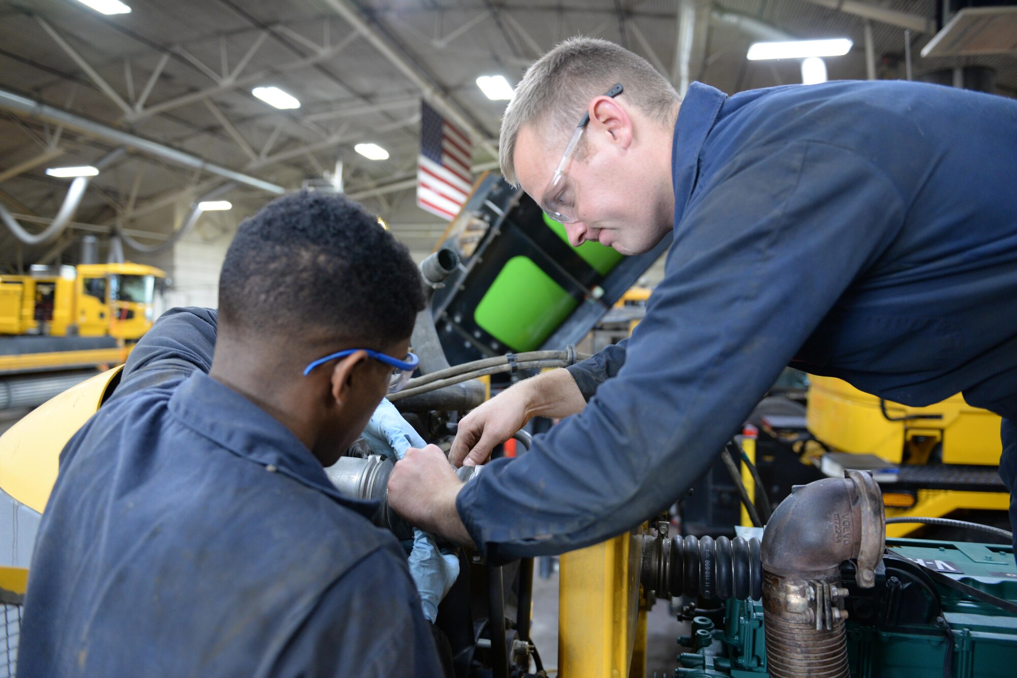 Airman 1st Class James Walton and Senior Airmen Brian Baker, both vehicular equipment maintainers at the 673d Logistics Readiness Squadron Heavy Equipment Shop, work on an engine installation on an Oshkosh H-series truck Aug. 29, 2017, at Joint Base Elmendorf-Richardson, Alaska. The 673d LRS is responsible for inspecting, troubleshooting and all snow-removal truck repairs at JBER.