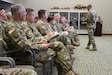 U.S. Army Soldiers sit in an auditorium while the commander briefs.