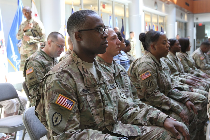 Soldiers sitting in an audience, listening to a presentation.