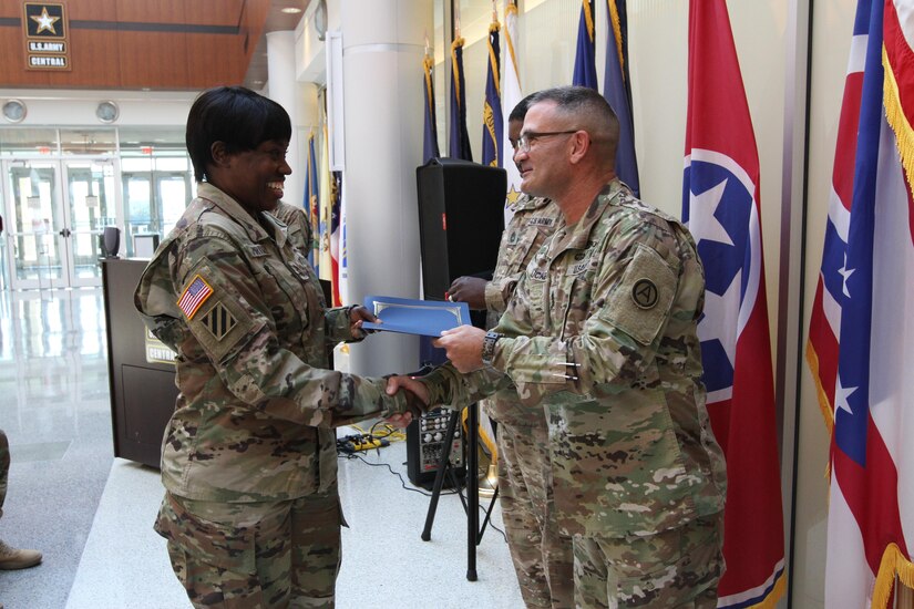 Soldier receives a handshake and graduation certificate from superior.