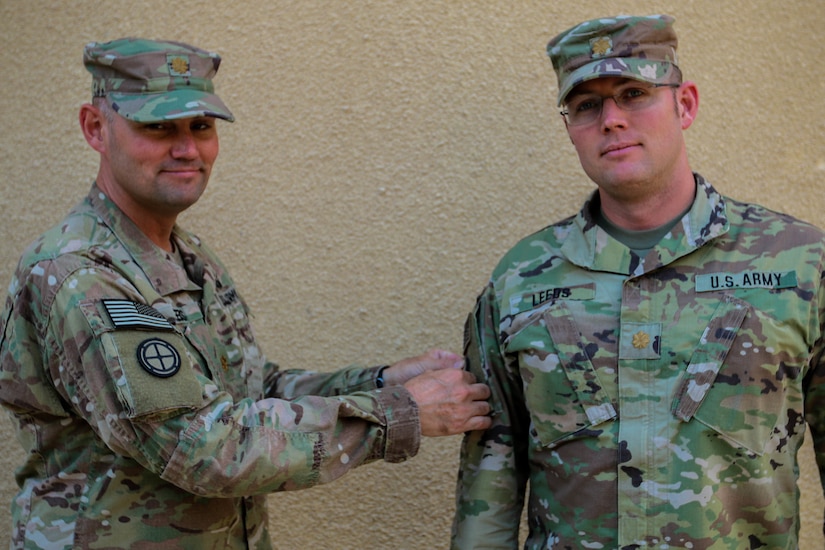 U.S. Army soldier puts combat patch on another soldier's uniform.