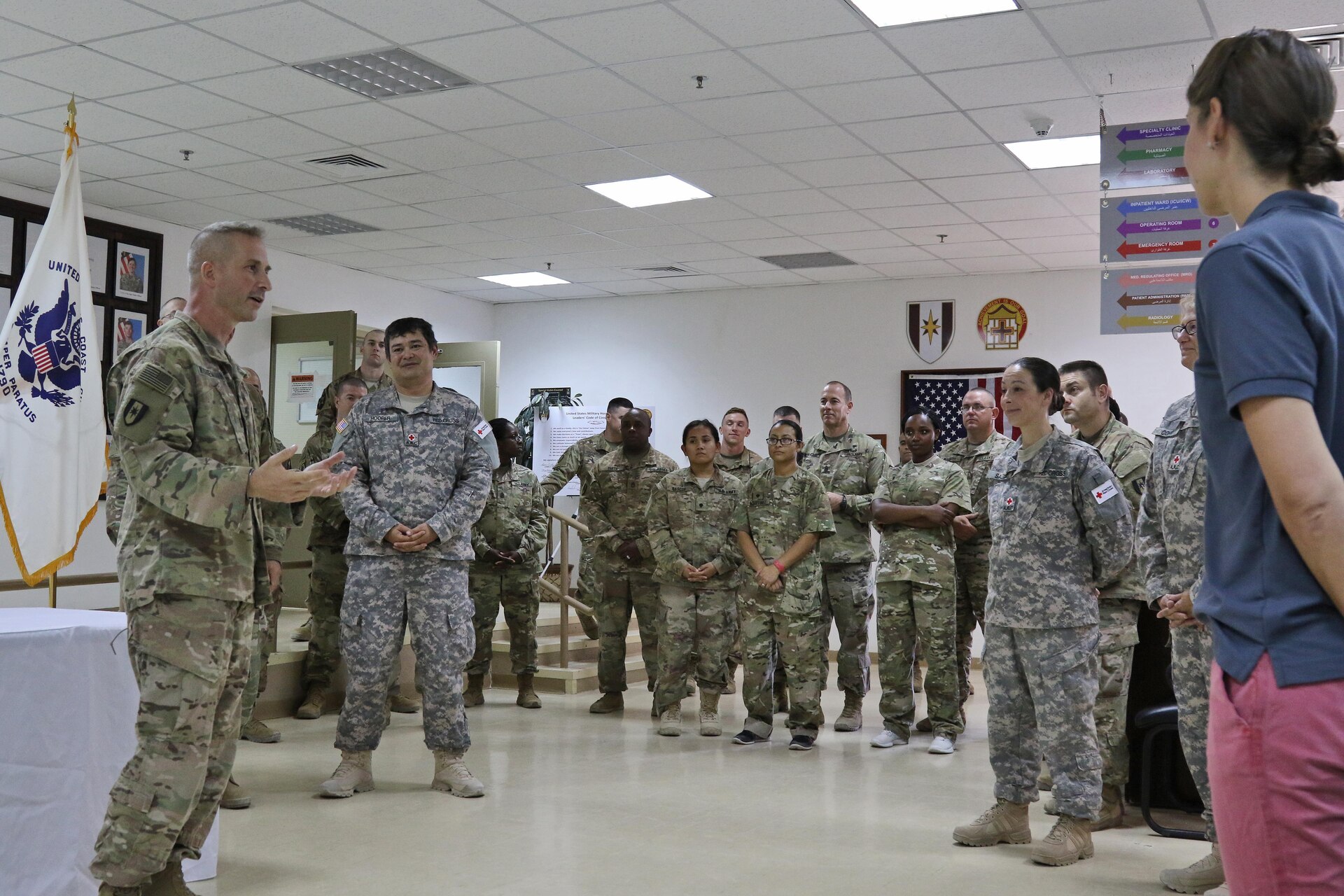 One soldier talking to a group of soldiers and civilians.