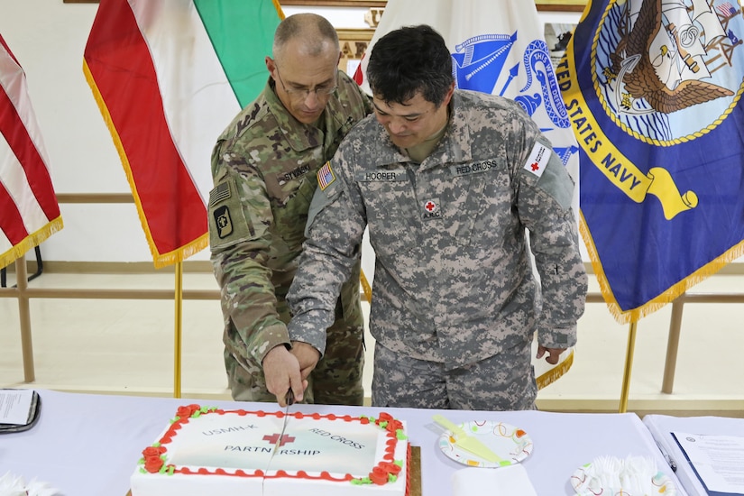 Two U.S. soldiers slice a cake.