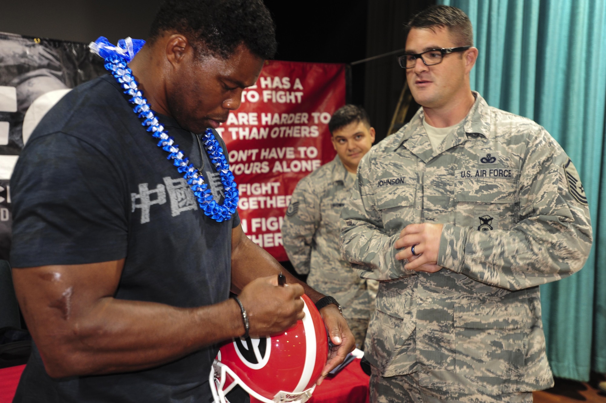 Herschel Walker, former professional football player, signs a football helmet for Master Sgt. Adam Johnson, 647th Security Forces Squadron, after talking with Airmen about the importance of mental health care at the Hickam Memorial Theatre, Joint Base Pearl Harbor-Hickam, Hawaii, Sep. 6, 2017.