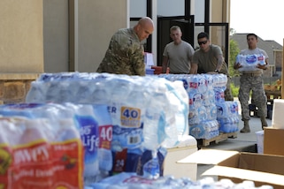 Soldiers pull pallets of water out a door.