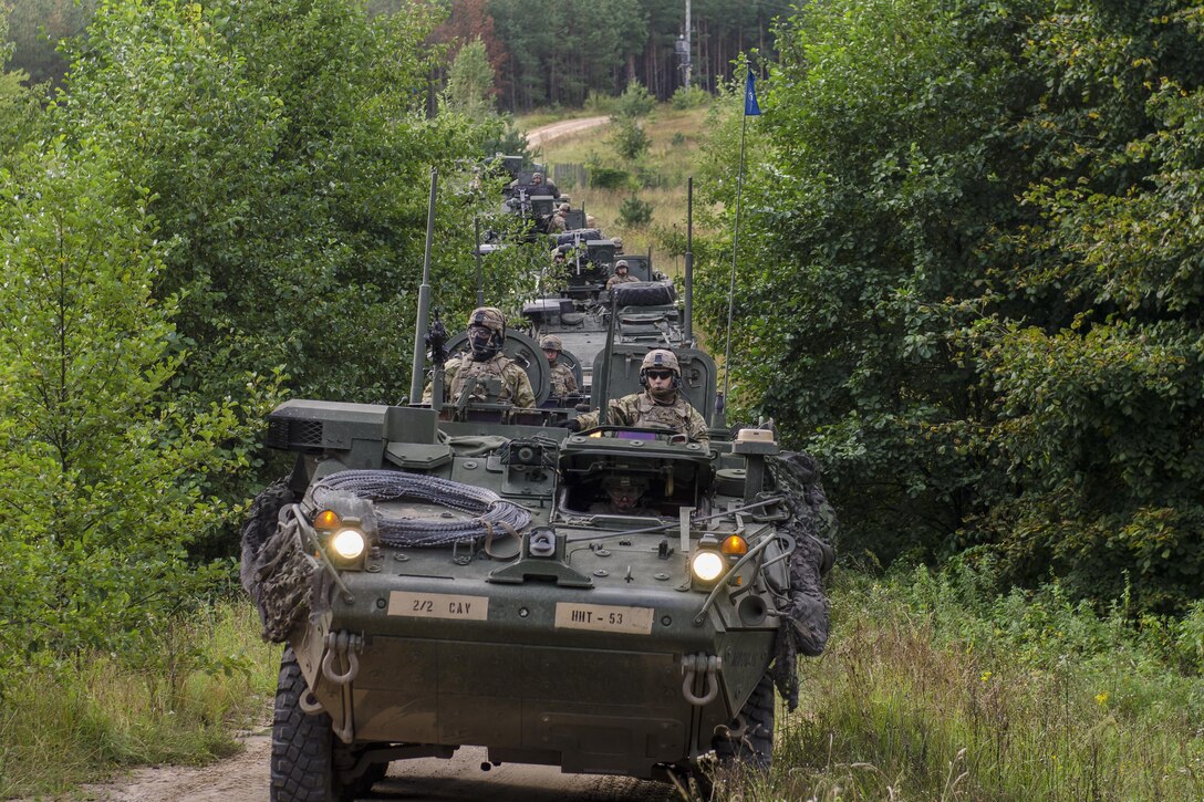 A long line of tanks moves forward along a road.