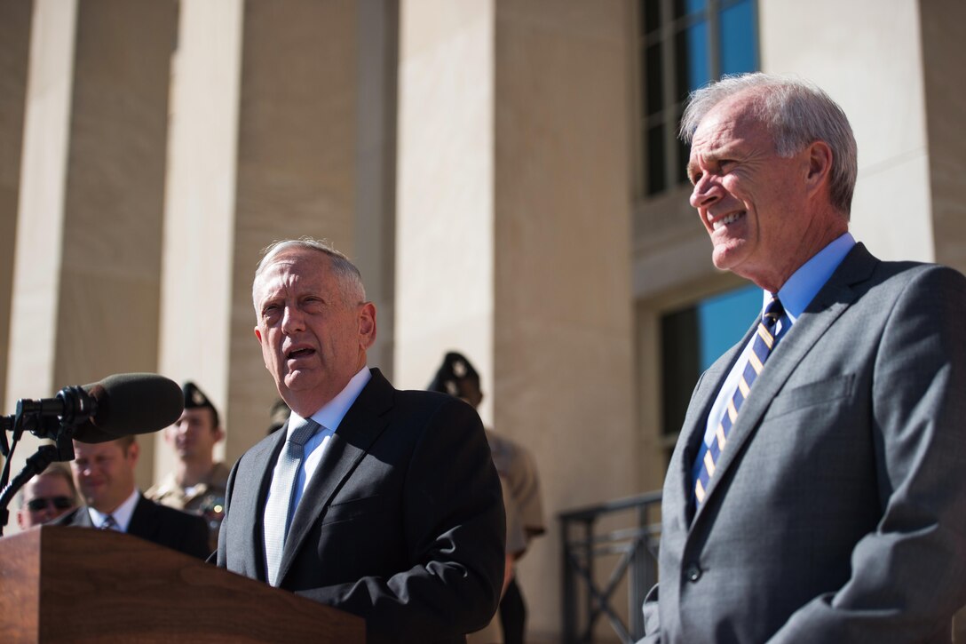 Defense Secretary Jim Mattis speaks at a podium standing next to Secretary of the Navy Richard V. Spencer.