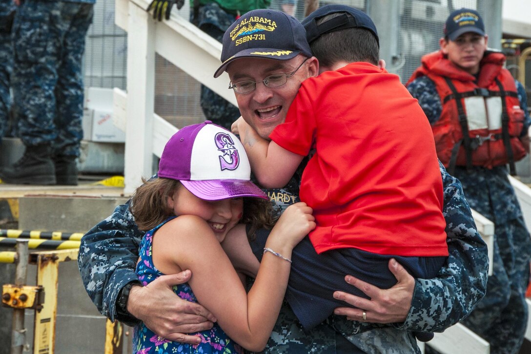 A sailor hugs his two children.