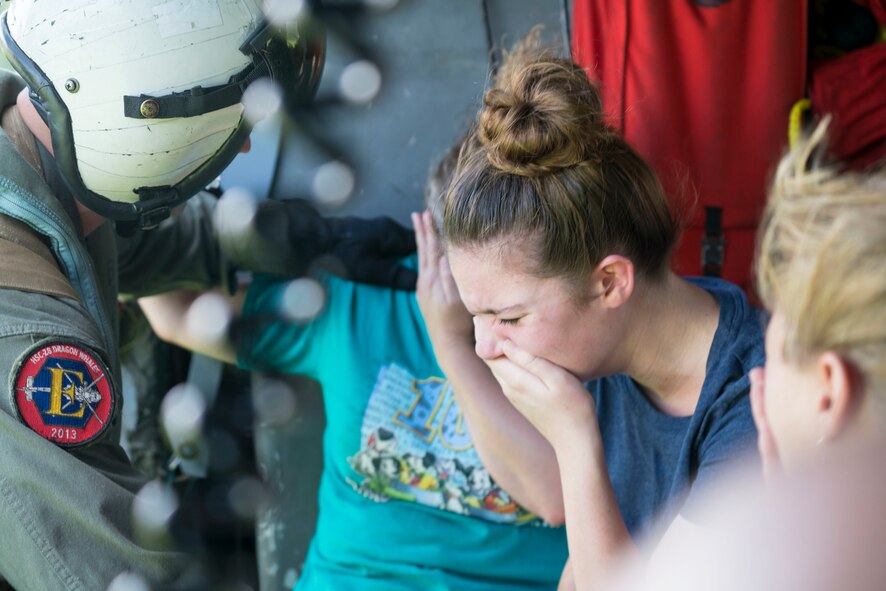Naval Aircrewman (Helicopter) 2nd Class Jansen Schamp, assigned to the Dragon Whales of Helicopter Sea Combat Squadron (HSC) 28, reassures a family after a rescue at Pine Forest Elementary School, a shelter that required evacuation after flood waters from Hurricane Harvey reached its grounds. The Western Air Defense Sector provides critical
communications relay between the Texas Emergency Operations Center and the U.S. Navy in order to rescue over a hundred people from the school grounds.
