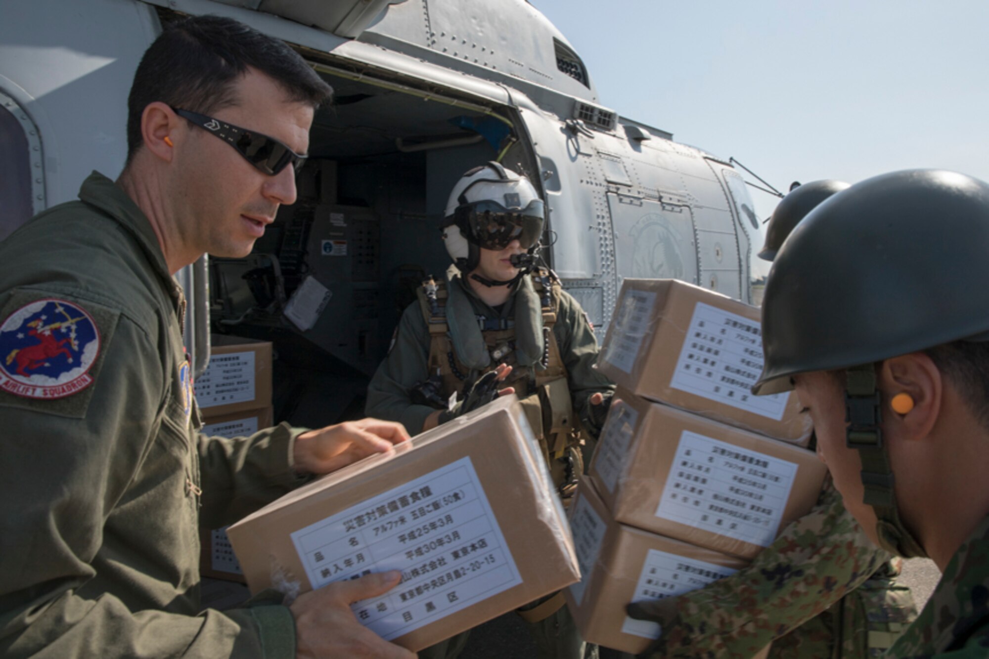 A U.S. Navy MH-60R flight engineer and U.S. Air Force Tech. Sgt. Nicholas Poe, 459th Airlift Squadron UH-1N special missions aviator, pass simulated relief supplies to Japan Ground Self-Defense Force members assigned to the 1st Logistics Regiment, JGSDF Nerima Station, at Yokota Air Base
