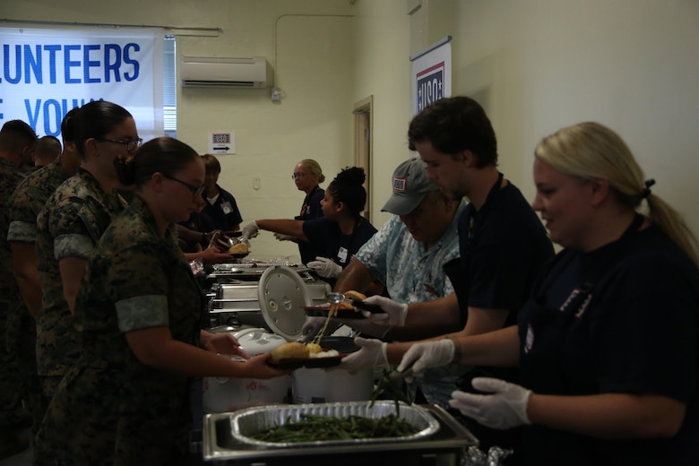 CAMP FOSTER, OKINAWA, Japan – Volunteers serve food to Marines after the grand reopening ceremony Aug. 30 at the Camp Foster USO, Okinawa, Japan.