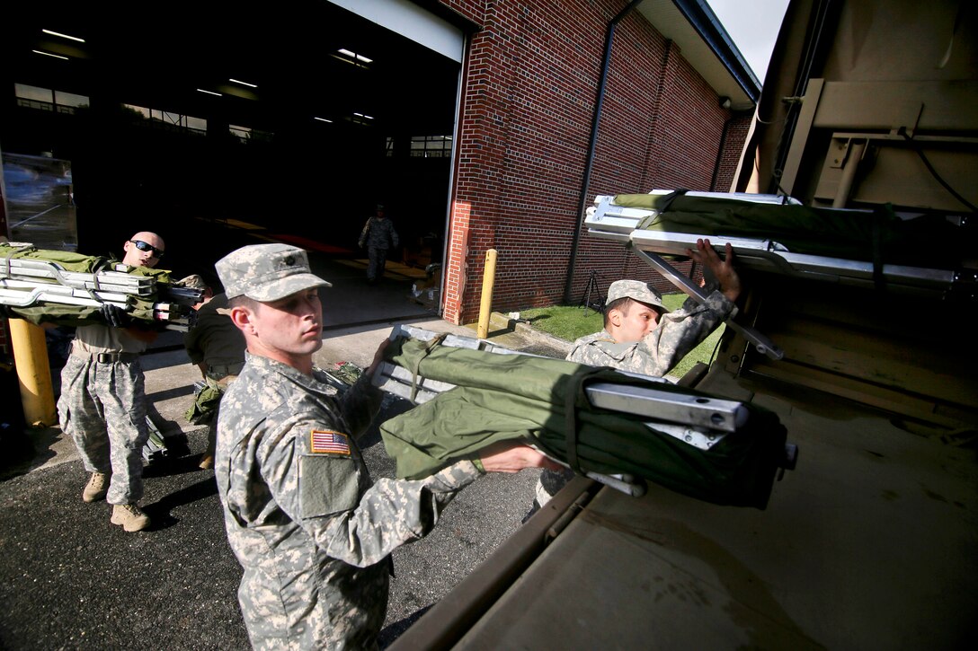New Jersey Army National Guardsmen load cots onto a vehicle.