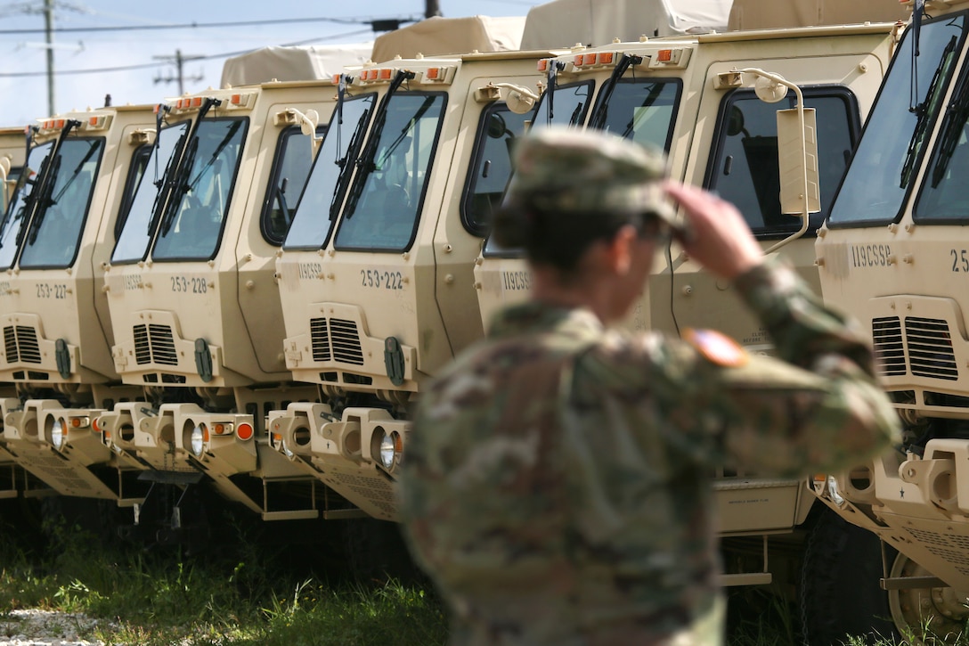 A soldier walks past a row of military vehicles.