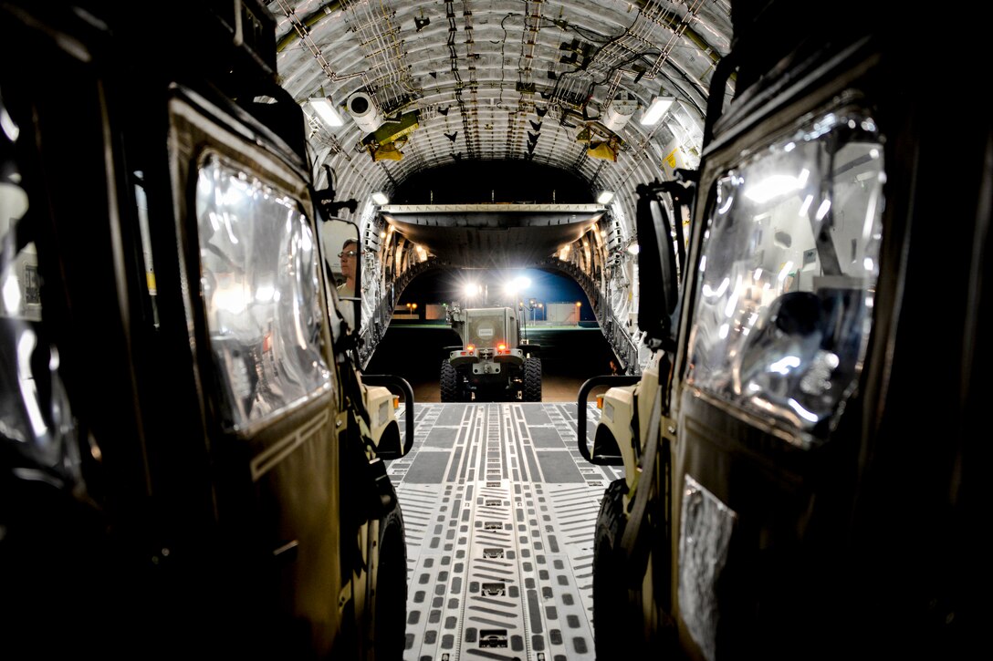 Airmen load vehicles and supplies onto a C-17 Globemaster III aircraft.