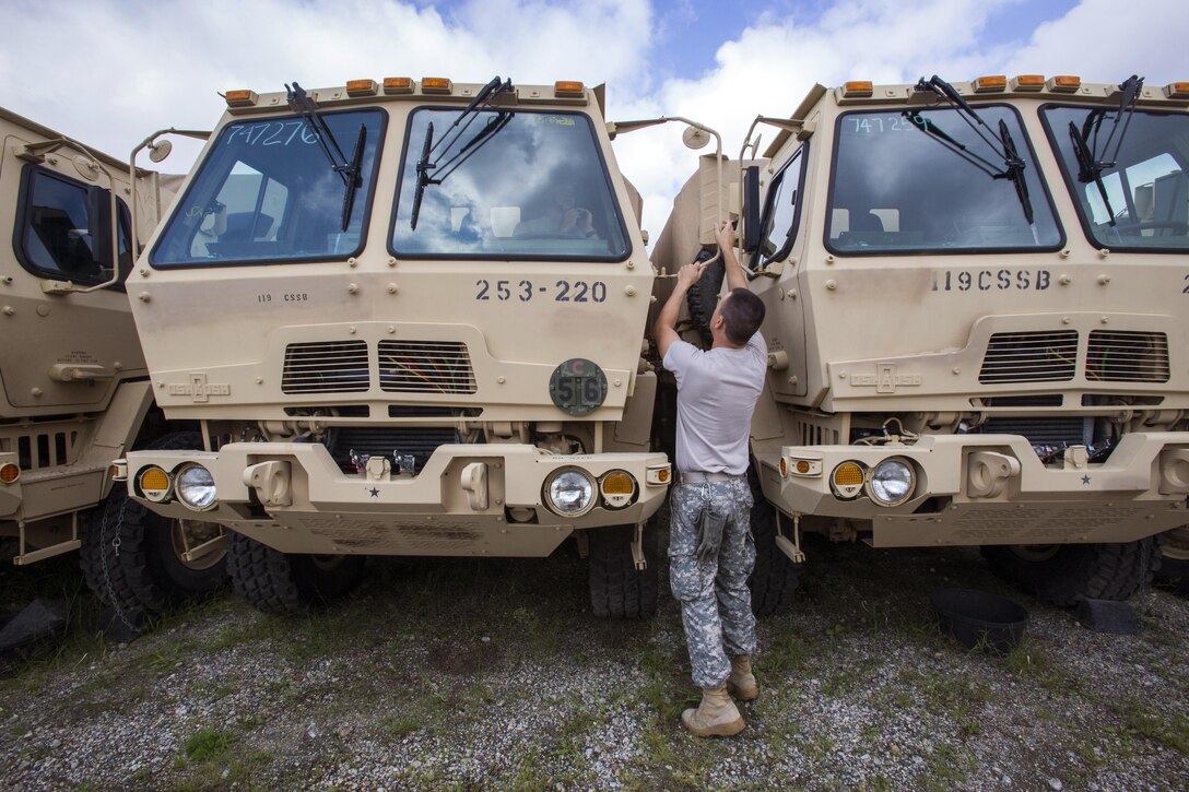 New Jersey Army National Guard Sgt. Maksym Gunko adjusts a mirror on a light medium tactical vehicle at Cape May Courthouse, N.J.