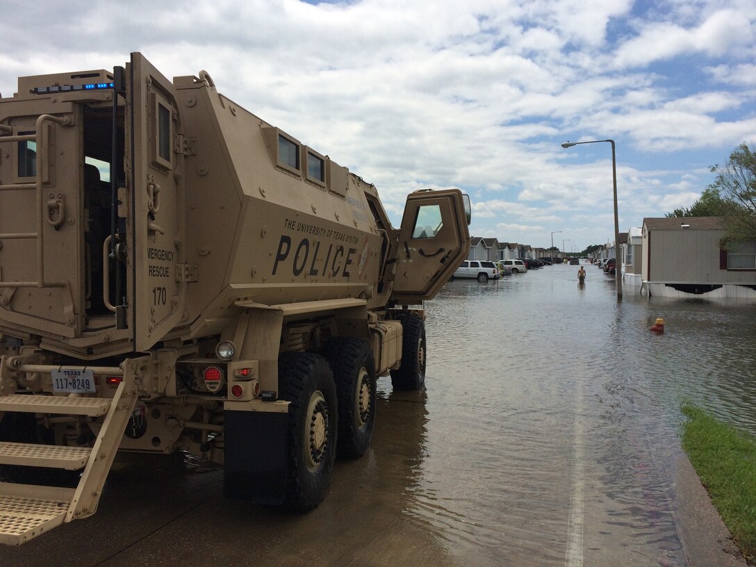 A mine resistant, ambush protected vehicle sits with doors open on a flooded street