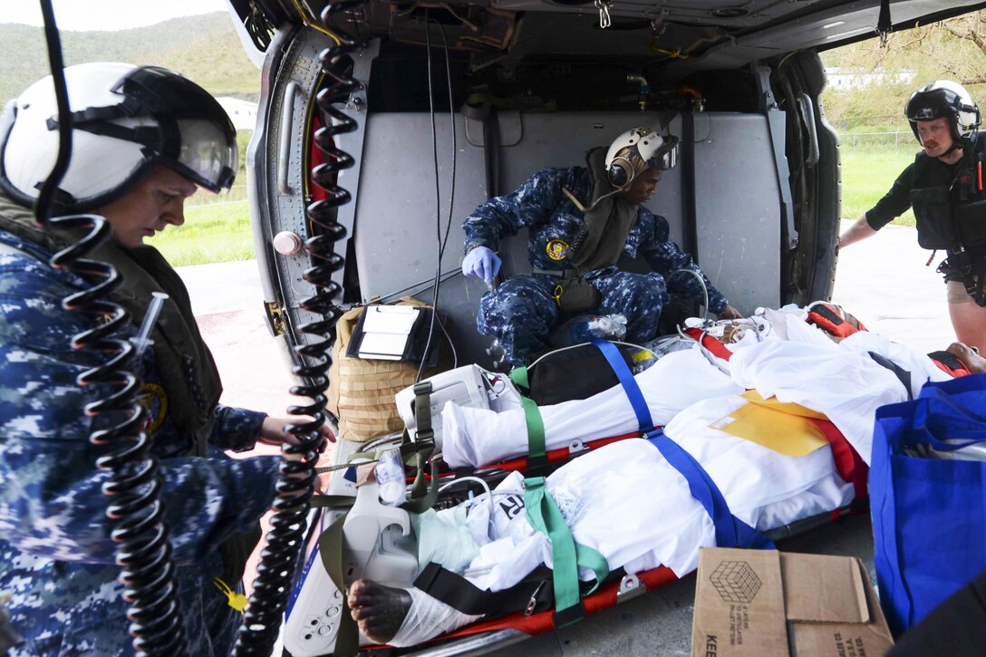 Sailors load hurricane evacuees into a helicopter.