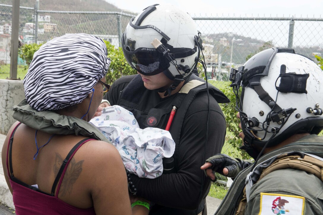 Sailors help a mother and child following Hurricane Irma.