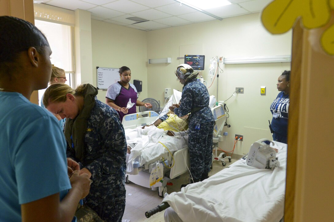 Sailors and civilians talk in a hospital room.