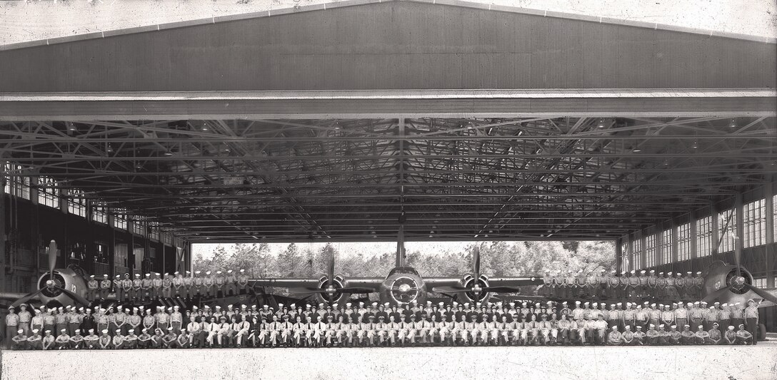 IMAGE: 1940s? Early '42?
Group Photo in Hangar-on eft wing of plane #13-15 airmen, on right wing of
plande 92-16 airmen, sitting on ground to left-13 airmen, seated-41, women standing in middle row-31,
last row-76, total 203 personnel. Planes visible in Photo: Twin prop-#34, Single props-#13, #92, #91,
#16