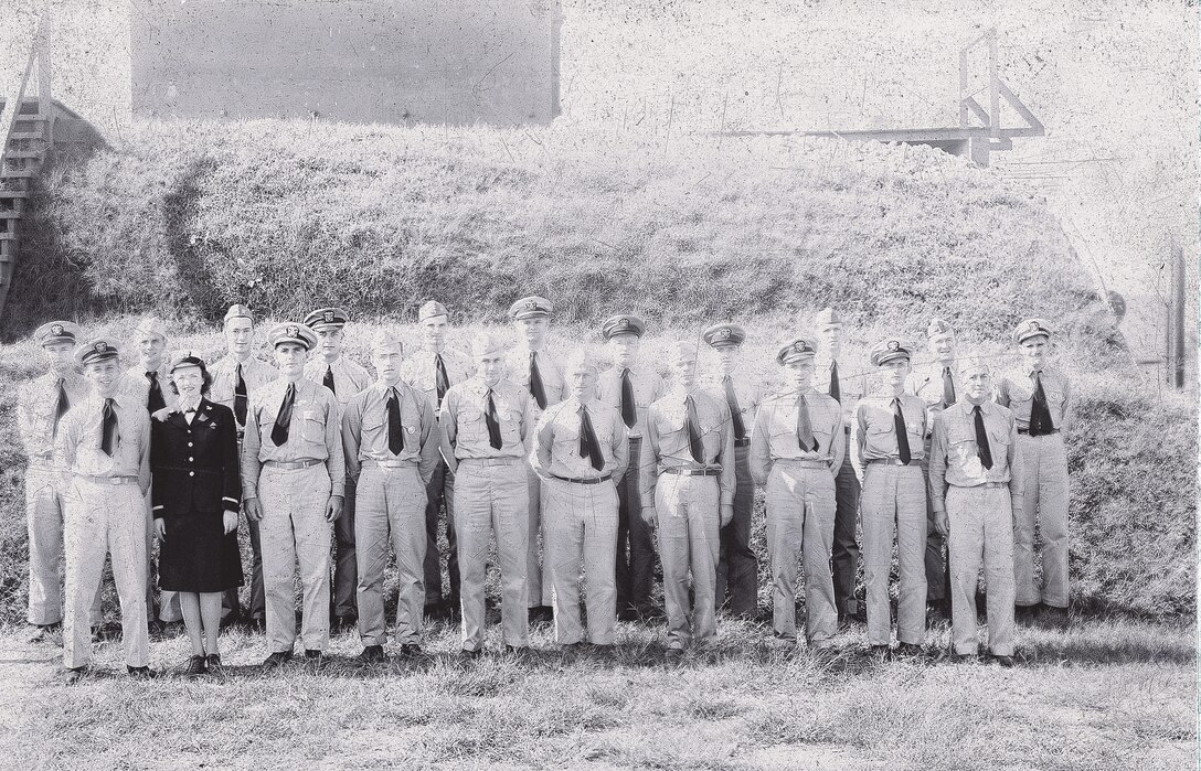 IMAGE:10/7/1944
[Lt. Philipchuk returned to Dahlgren and worked in TE until he died young CA 1970. Lt. Hersey might be Dr. Alan Hersey, K Computer leader. Lt J.J. Glancy - became engineer and community leader.] [W.W. Meyers stayed in Dahlgren and became a division ehad in the new G department "wes"] In front of storage mound, Armor Department Officers, Front row L-R: Lt. (JG) C. Philipchuk, USNR: Ens. H.I. Olson, USNR: Lt. (JG) L.W. Mahinney, USNR: Lt (JG) Burstein, USNR: Comdr. G.K. Williams, USN: Comdr. H.S. Harnly, USN: Comdr. G.T. Atkins, USN: Lt. J.E. Sandberg, USNR: Lt. (JG) H.E. Brehm, USNR: Lt (JG) R.R. Hershey, USNR: Back Row L-R: Lt. H.R. Pflug, USNR: Lt. G.A. Rauch, USNR, Lt. D.E. Thomas, USNR: Lt. P.A. Krentel, USNR: Lt. M.R. Herman. USNR, Lt (JG) F.G. Brune, USNR: Lt. J.J. Clancy, USNR: Ens. S.S> Cross, USNR: Lt. (JG) W.W. Meyers, USNR: Lt R.C. Smith, USNR: Ens. C.H. Waldhauer, USNR; Not Present in Photo: Lt T.A. Priger, USNR: Lt. (JG) M.M. Sirota, USNR: and Ch. Gunner Glen Frazier, USN.