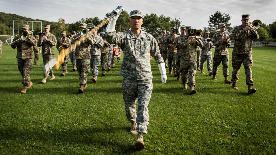 A drum major wields a staff while leading a marching band.