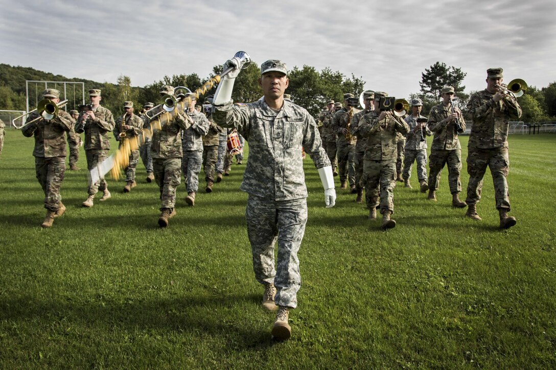 A drum major wields a staff while leading a marching band.