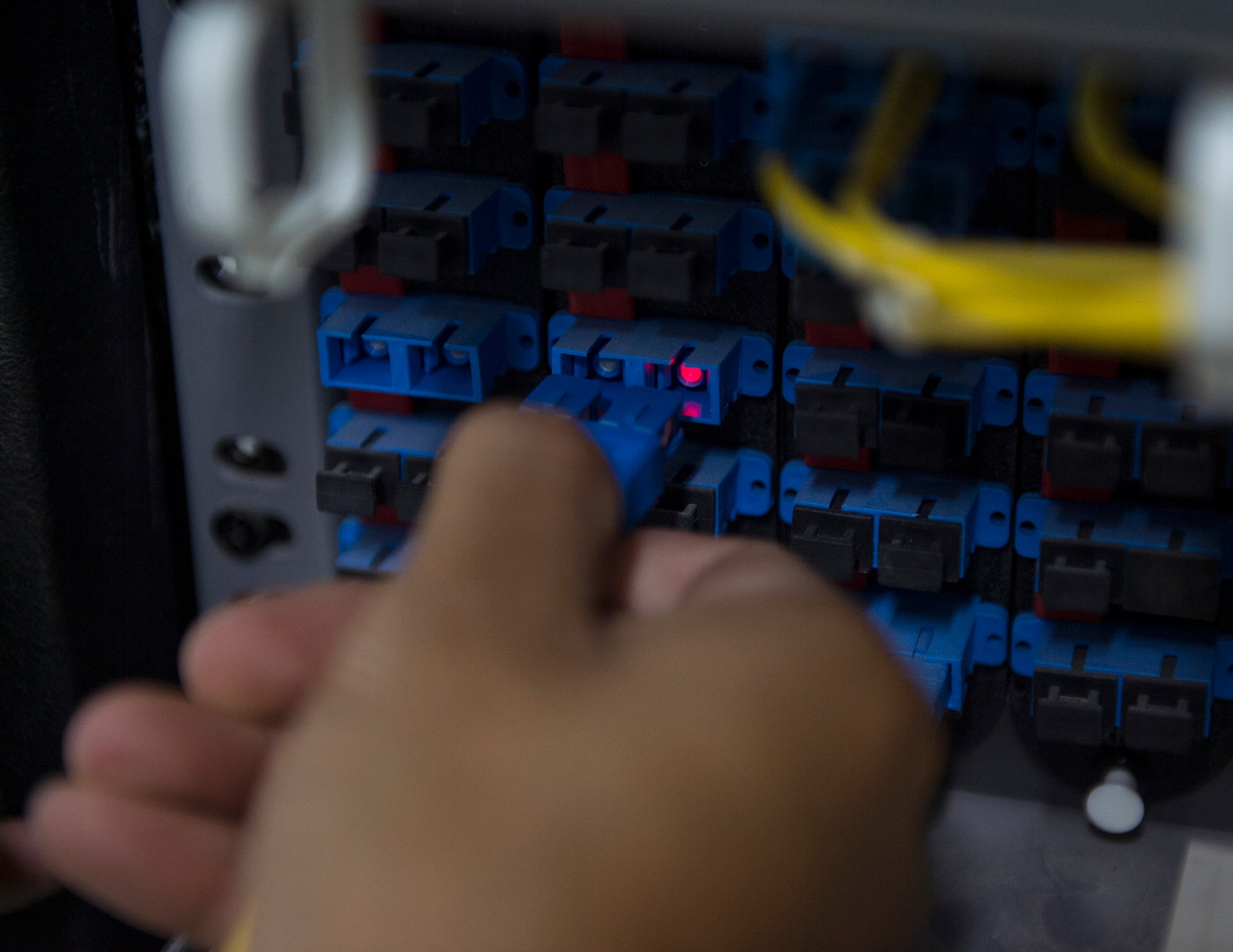 U.S. Air Force Senior Airman Monorom Tim, a network management technician with the 379th Expeditionary Communication Squadron, plugs in a fiber cable at Al Udeid Air Base, Qatar, July 14, 2017.