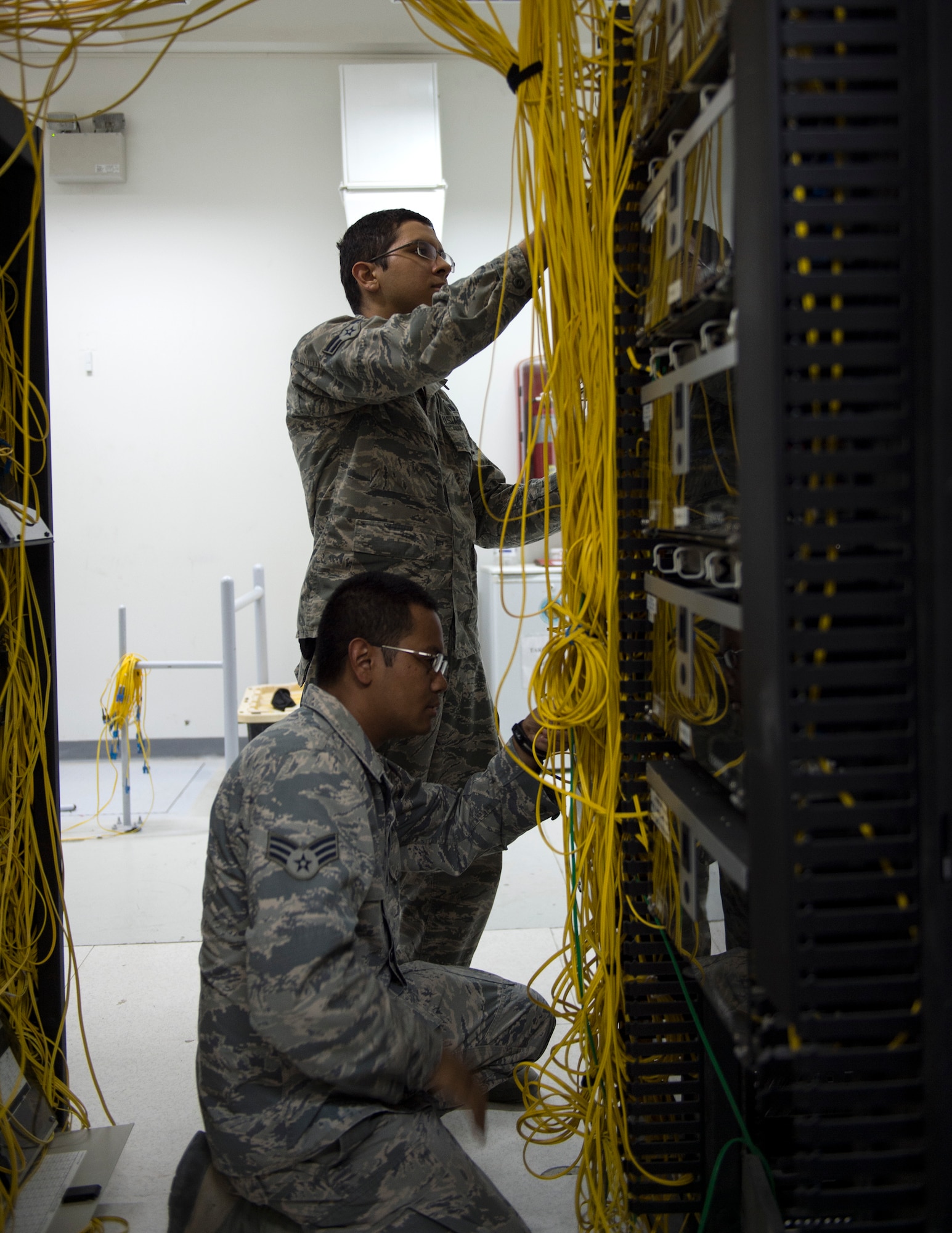 U.S. Air Force Senior Airman Monorom Tim, bottom, and Airman 1st Class Luis Gonzalez, network management technicians with the 379th Expeditionary Communication Squadron, check the fiber cables at Al Udeid Air Base, Qatar, July 14, 2017.