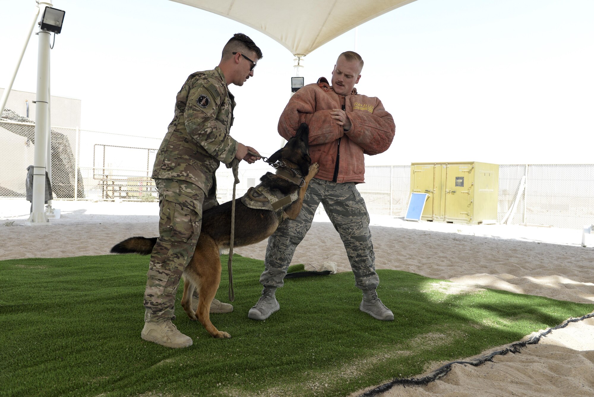 U.S. Air Force Senior Airman Louis Hurbis, military working dog handler assigned to the 379th Expeditionary Security Forces Squadron, is detained by fellow military working dog handler Staff Sgt. Brandon Stone and his military working dog Hugo, during a K-9 demonstration exercise at Al Udeid Air Base, Qatar, Aug. 17, 2017.