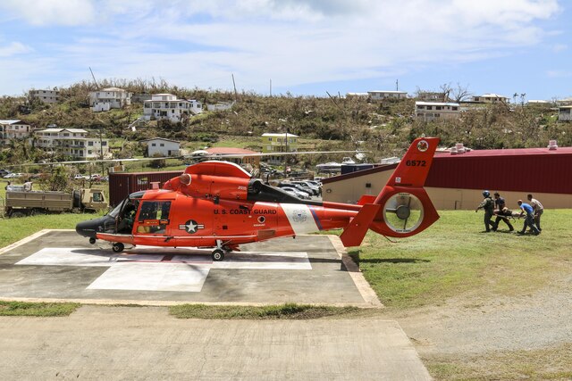 Coast Guardsmen carry a person a stretcher to a waiting helicopter. 