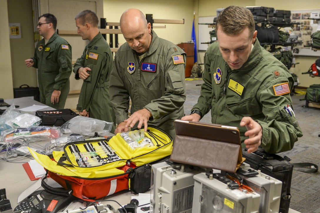 Airmen handle medical supplies on a table.