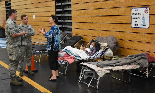 Florida Air National Guardsmen talk with a woman at a special-needs shelter.