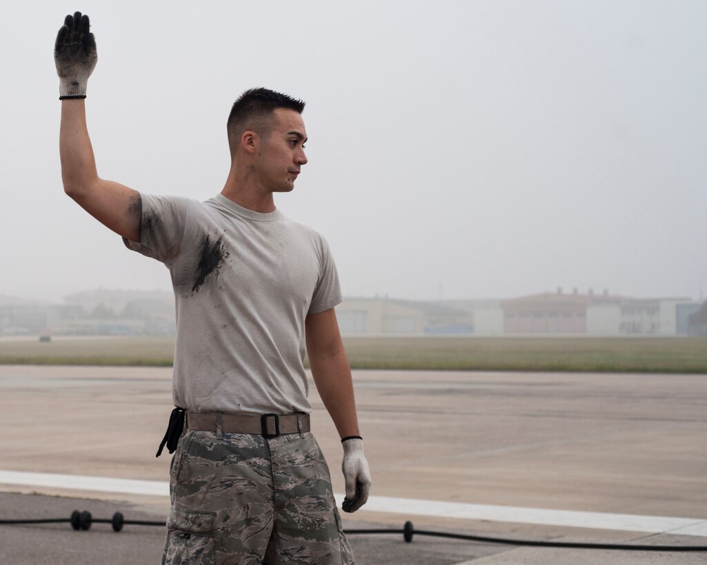 U.S. Air Force Senior Airmen Daniel Tomasek, 8th Civil Engineer Squadron electrical power production journeyman, signals his counterparts while reeling in the barrier tape on the aircraft arresting system at Kunsan Air Base, Republic of Korea, Sept. 9, 2017. The nylon barrier tape is woven into a rubberized material similar to that found in a golf ball which gives it elasticity. The material must be reeled in on its 66-inch spool properly to ensure that when an aircraft’s hook catches the steel cable the tape can extend a few feet before bringing the out-of-control aircraft to a safe halt. (U.S. Air Force photo by Staff Sgt. Victoria H. Taylor)