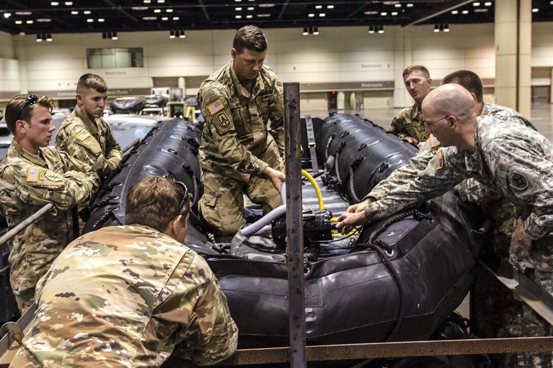 Soldiers surround an inflatable boat in a trailer.