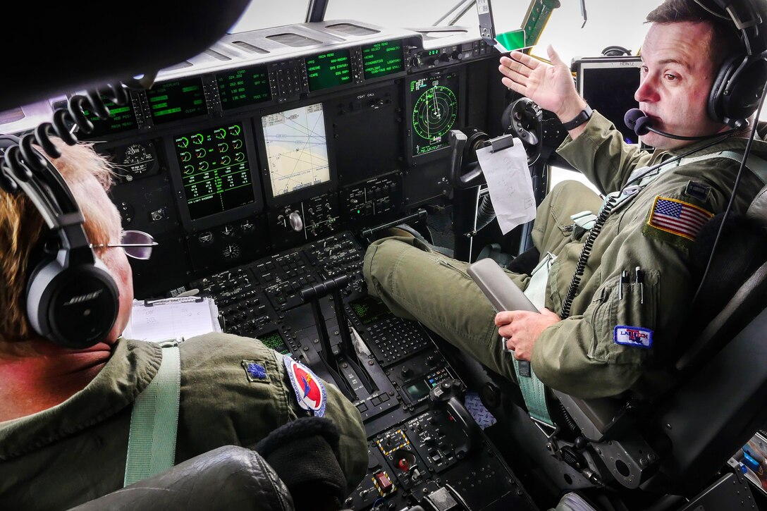 Two Air Force pilots sit behind the controls of an airplane.