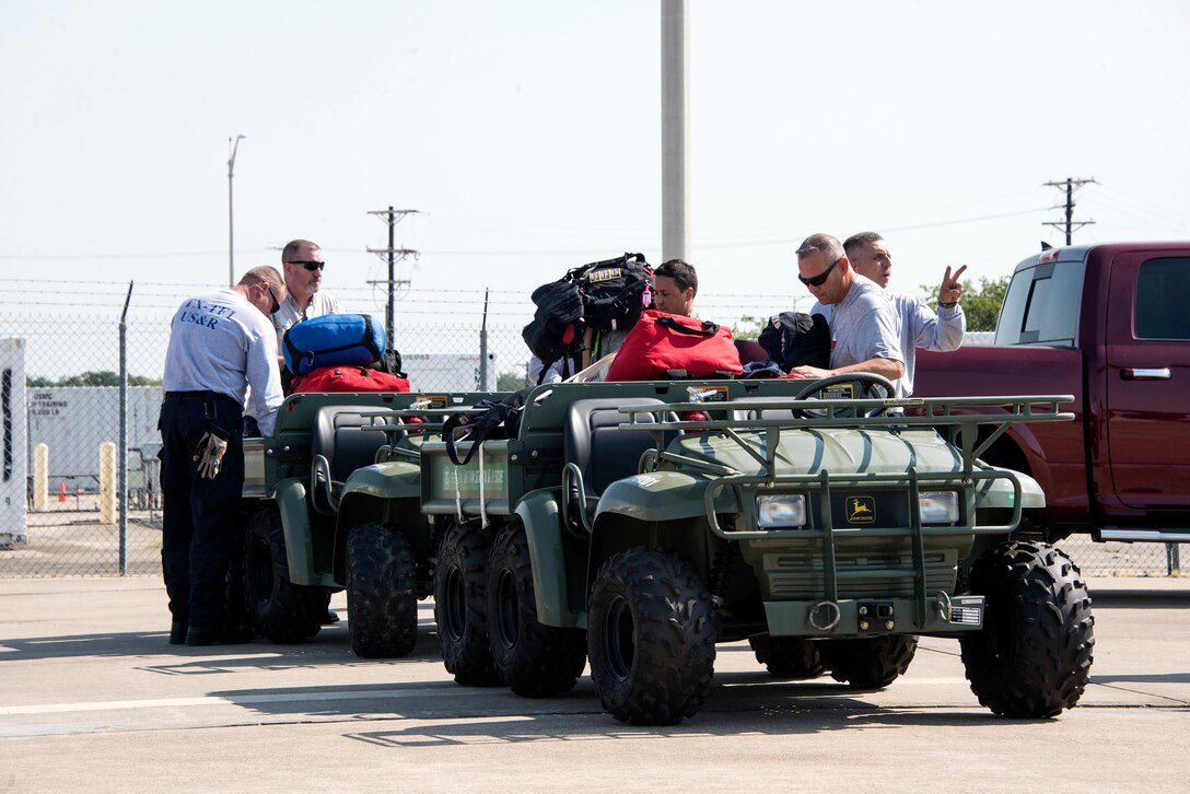 Personnel move and check bags on the back of all terrain vehicles.