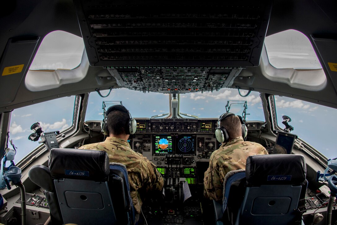 Two pilots sit in behind the controls of an aircraft.