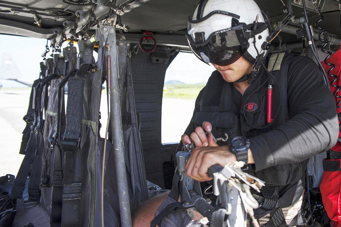 A sailor preps a helicopter to transport cargo.