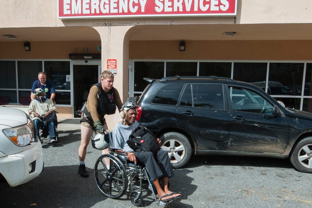 A sailor pushes a patient in a wheelchair.