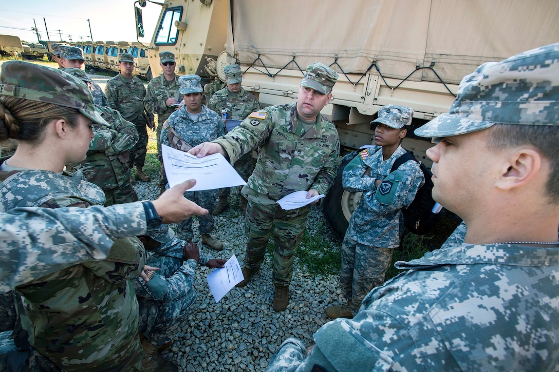 A soldier hands papers to another soldier.