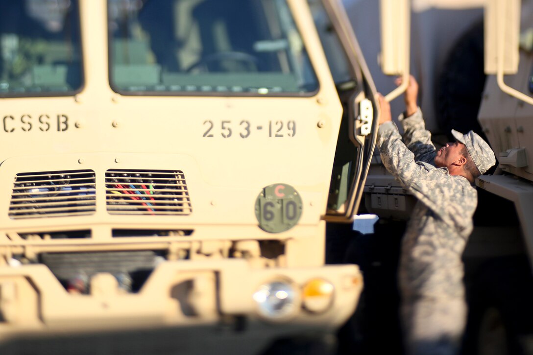 A soldier prepares gear and light medium tactical vehicles.