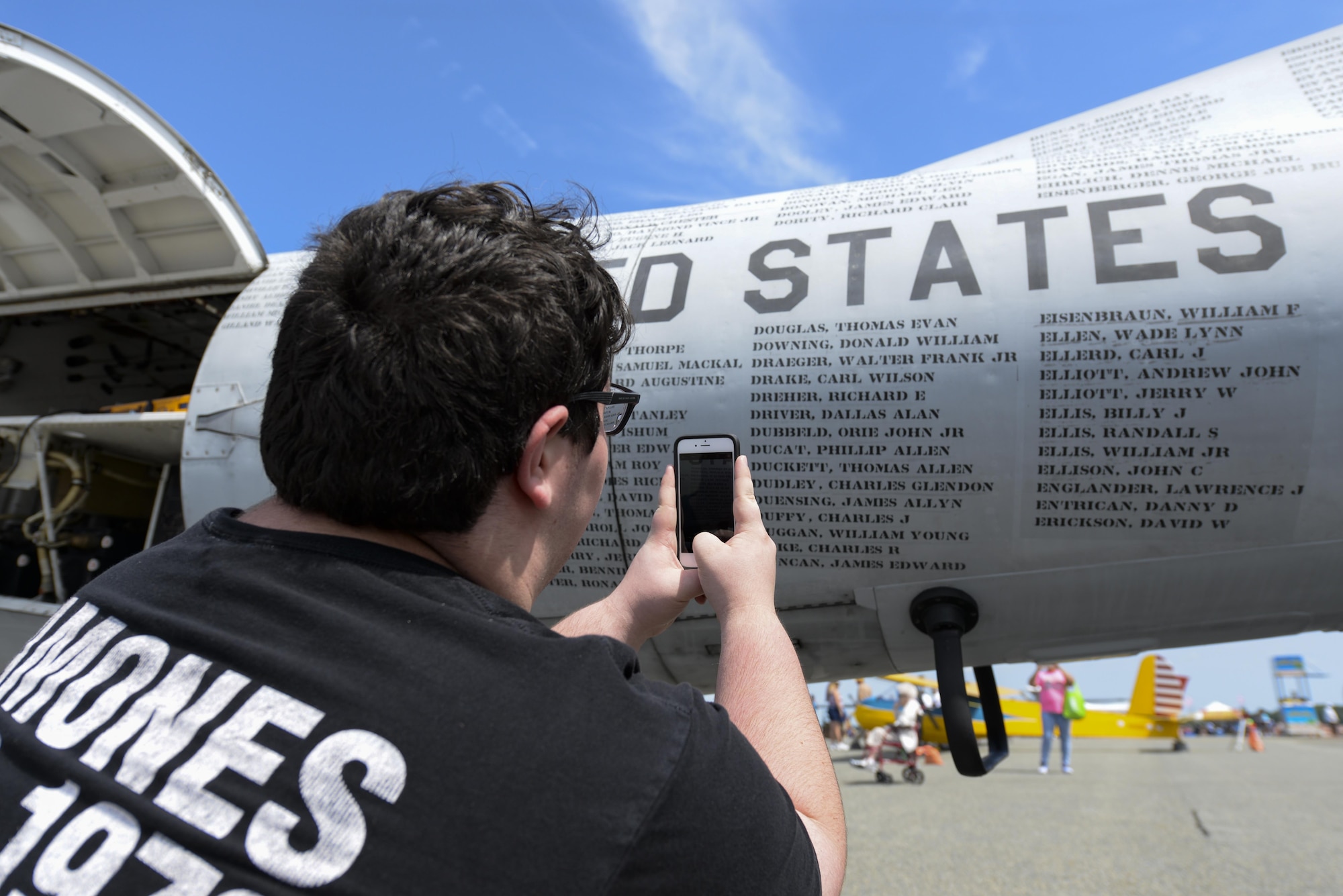 A guest of Team Dover takes photos of names on Mohawk Airshow’s Army OV-1 Mohawk Vietnam POW/MIA flying monument. The Army flew the OV-1 during the Vietnam War through Operation Desert Storm to gather battlefield surveillance and provide light strike capabilities. (U.S. Air Force photo by Staff Sgt. Aaron J. Jenne)