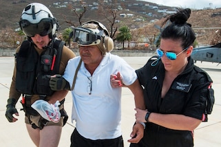 Two sailors escort a patient to safety.